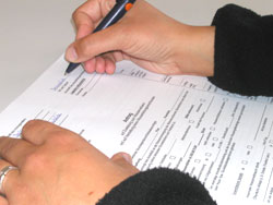 Zwei Hände und ein Antragsformular, die rechte Hand füllt das Formular aus.