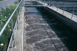 Detail einer Kläranlage: ein rechteckiges Becken, in dem sich Wasser kräuselt.