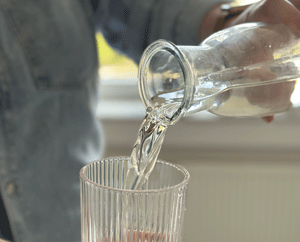 Wasserfalsche befüllt ein Glas.