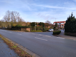 Eine leere Straße mit der Einmündung in ein Wohngebiet.