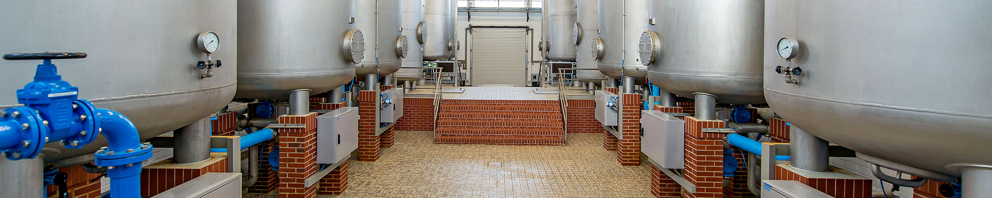 Zwei Reihen Kesselbehälter in der Halle eines Wasserwerks