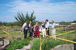 Sechs Menschen in sommerlicher Bekleidung stehen miteinander sprechendauf der Grünfläche eines Wasserwerkgelände