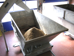 Ein offener Container in einer Lagerhalle mit einem Haufen Sand darin.