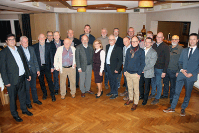 Eine Gruppe von 22 Menschen steht in einem Sitzungssaal