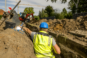 Mann arbeitet im Rohrgraben für Trinkwasserleitung