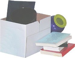 Ein Umzugskarton, in dem diverse Haushaltsgegenstände liegen, daneben ein Stapel Bücher.