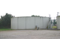 Seitenansicht der Betonumrandung des kreisrunden Schlammspeichers.