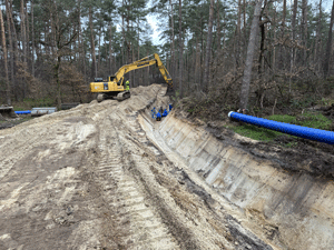 Rohrgraben im Wald mit Bagger und Wasserleitung