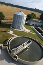 Luftbild des kreisrunden Vorklärbeckens, dahinter der 12 m hohe Faulgasspeicher.