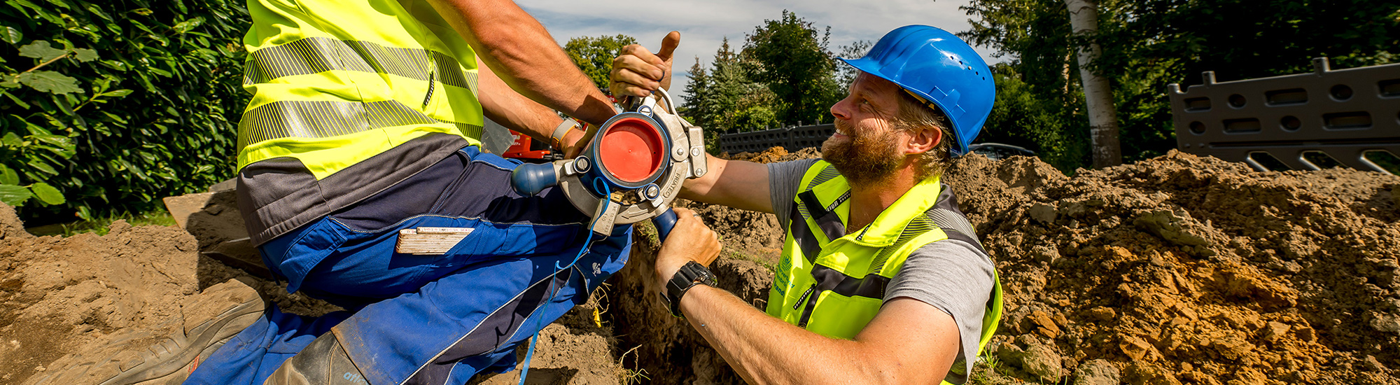 Zwei Arbeiter legen eine Leitung für Trinkwasser in die Erde.